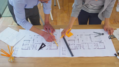 arquitectos masculinos y femeninos que trabajan en la oficina mirando los planes para un nuevo edificio en el escritorio