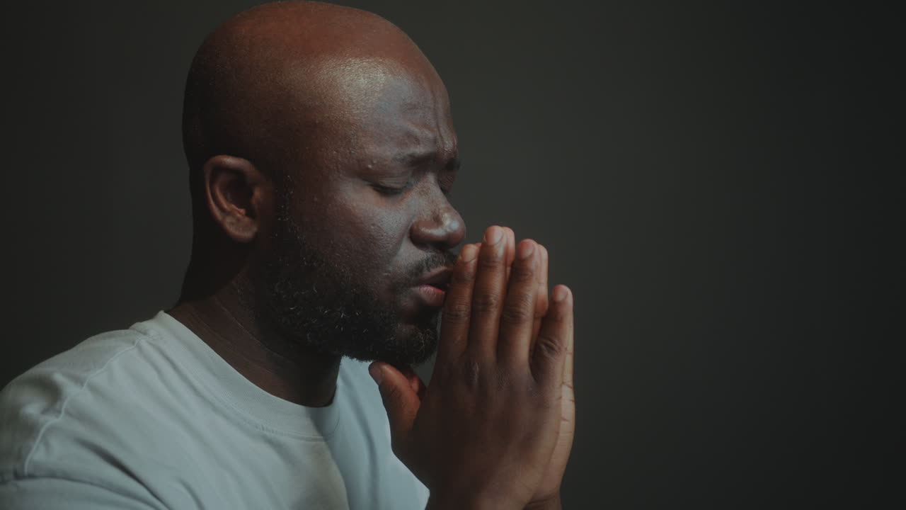 African American Man Holding Hands Together and Saying a Prayer