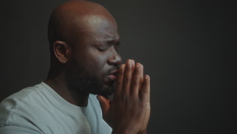 african american man holding hands together and saying a prayer