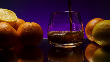 pouring whiskey into a glass with citrus fruits