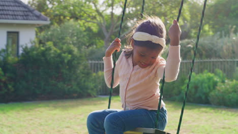 two children playing on a swing in their backyard