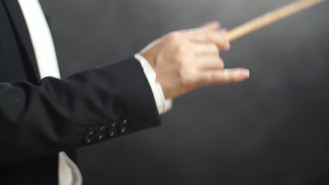 지휘자 손이 지이를 들고 검은 스튜디오에서 움직이는 근접한 측면 시각