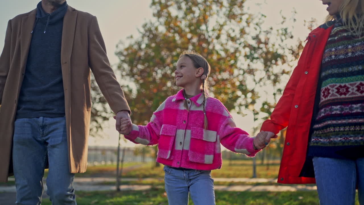 A family holding hands and walking together outdoors in the fall