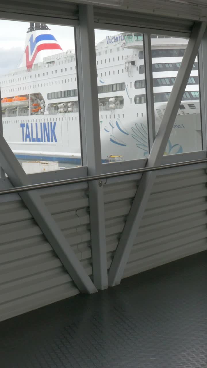 People walking along a bridge with a ferry in the background
