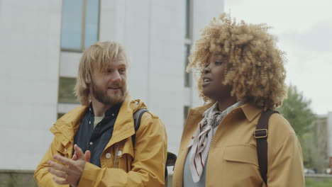 diverse friends or students in yellow jackets having a conversation outdoors