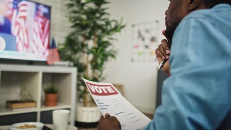 Handheld-video-of-man-watching-tv-and-holding-vote-document