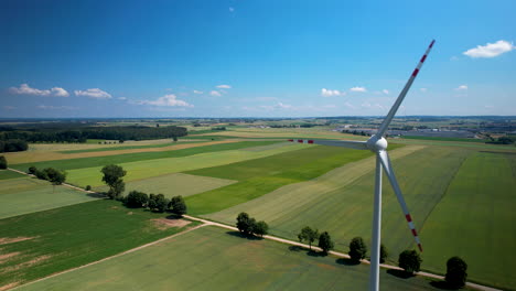 Aerial-Close-up-Rotating-Wind-Turbine-Blades-With-Agricultural-Crop-Fields-in-Backdrop-on-Spring-Sunny-Day