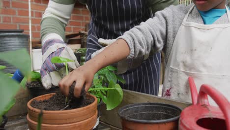 Glücklicher-älterer-Afroamerikanischer-Mann-Mit-Seinem-Enkel,-Der-Pflanzen-Im-Garten-Eintopft