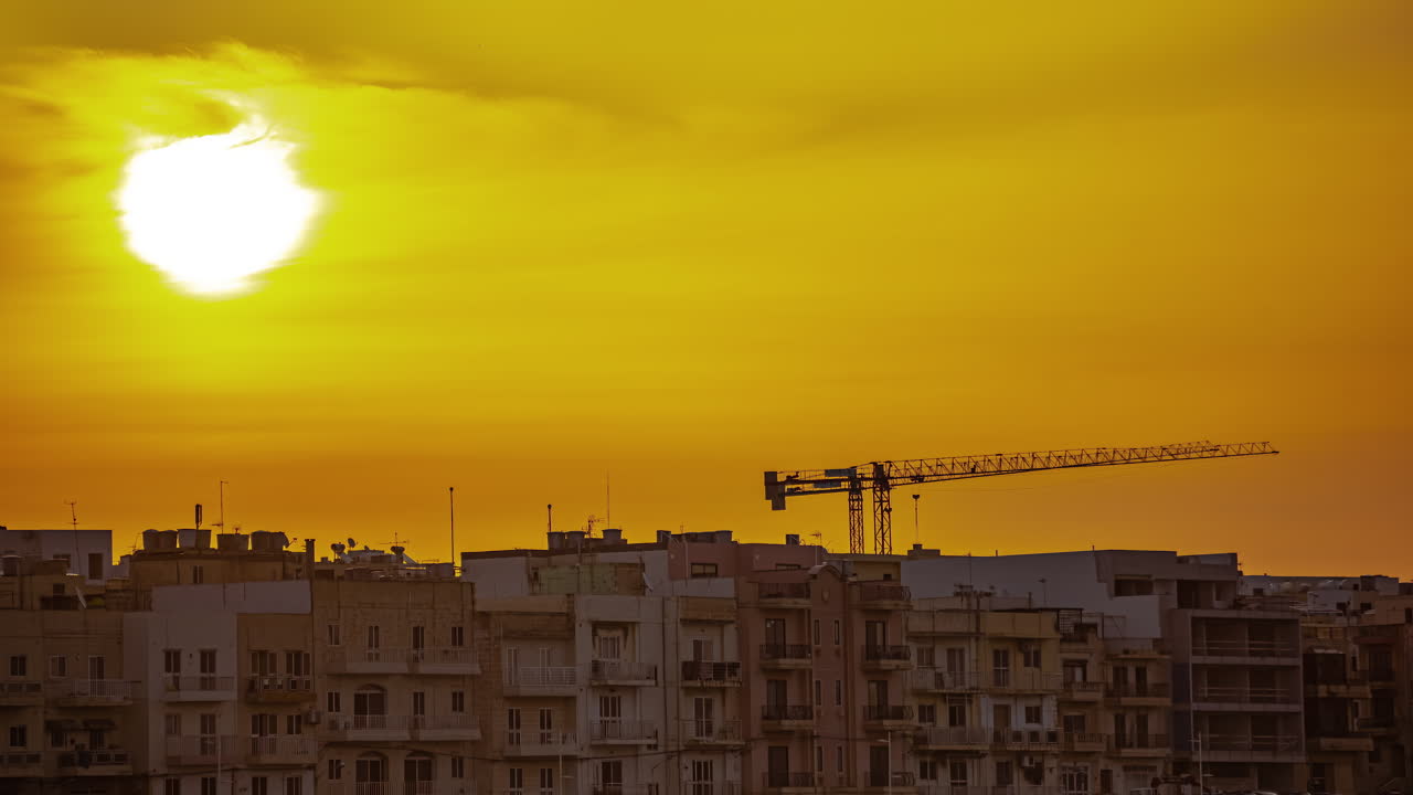 Timelapse de um nascer do sol com névoa no horizonte e um guindaste ao fundo.