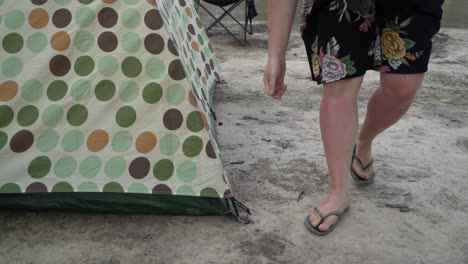 Pan-left-blonde-women-taking-out-pegs-packing-up-tent-camping-in-outback