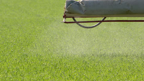 Slow-motion-telephoto-shot-on-edge-of-boom-sprayer-spraying-pesticides-on-crops