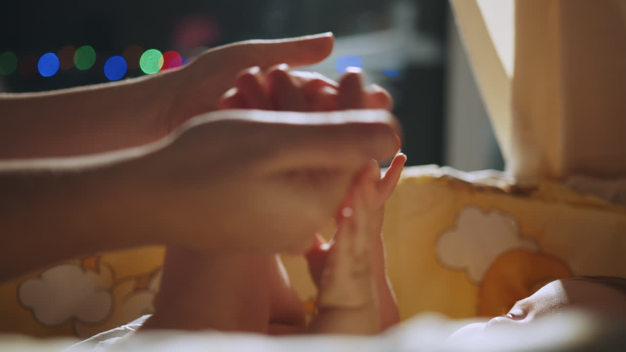 las mansas manos de la madre cuidan a un bebé dormido.