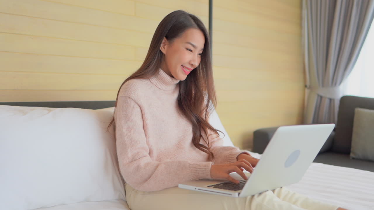 Asian woman with laptop in bed, work from home, social media using, entrepreneur