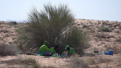 road workers sitting under the shade, having lunch during the midday break in the desert, uae