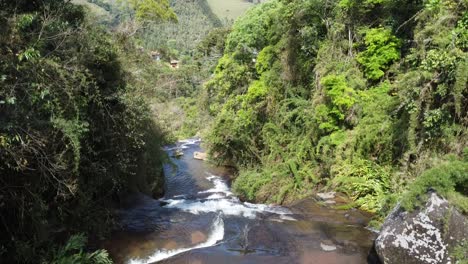 Drone-flying-down-the-waterfall-with-camera-movement-down-towards-the-water,-beautiful-trees-and-nature-around