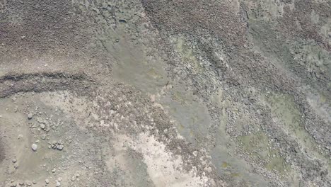 Top-down-ascending-drone-view-of-rocky-beach-in-St