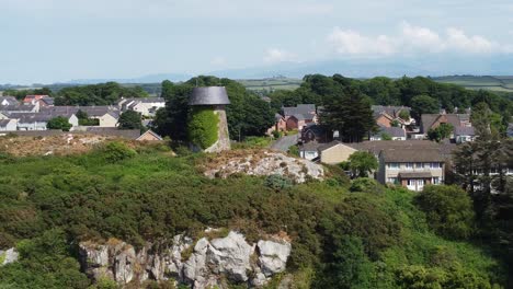 Llangefni-windmill-ivy-covered-hillside-landmark-aerial-view-orbiting-Welsh-Snowdonia-countryside,-Anglesey