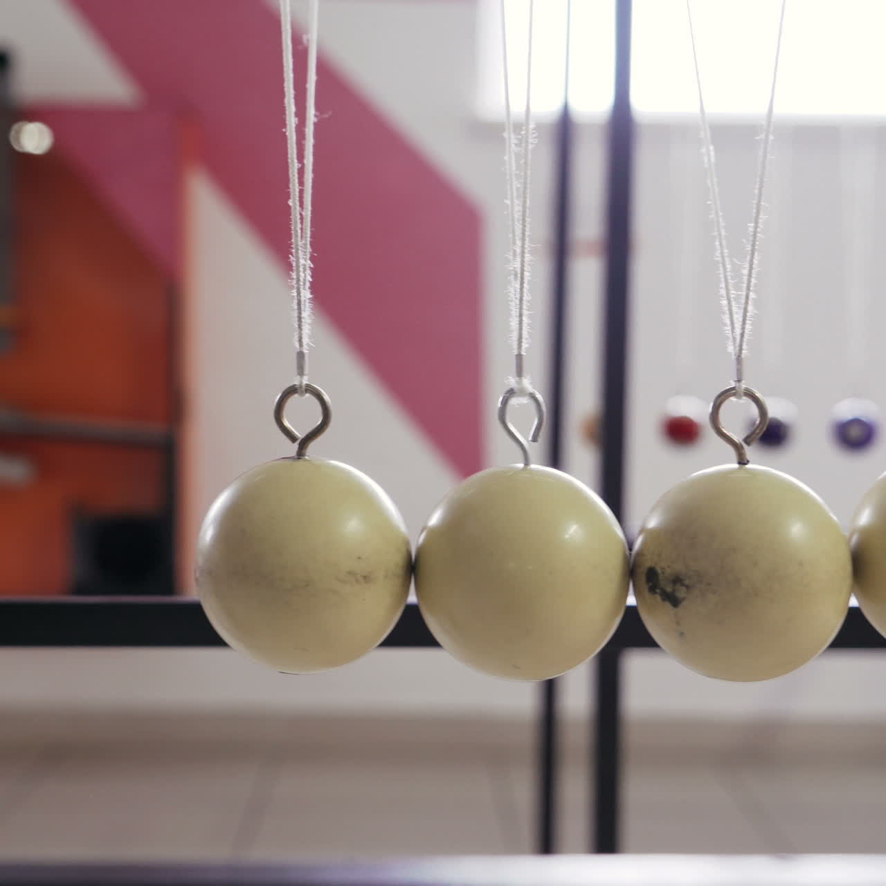 Hand holding a pendulum ball. Newton's cradle