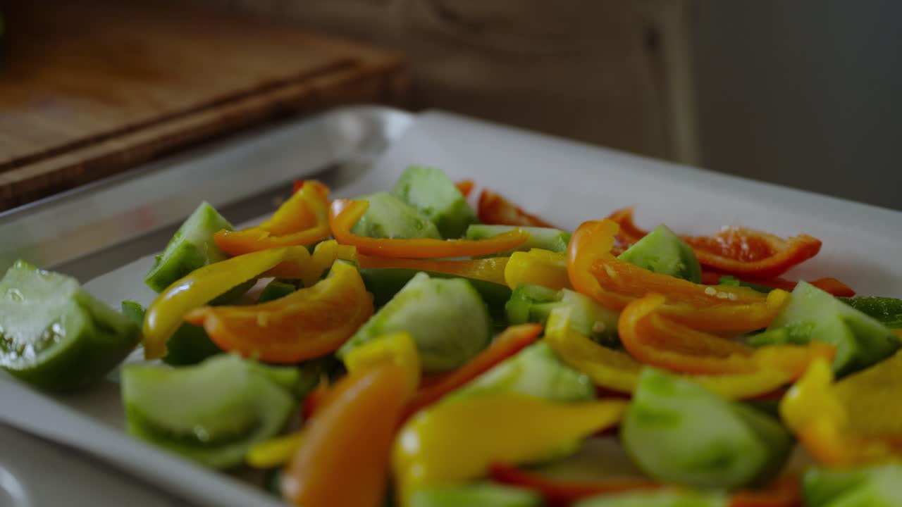 Closeup shot of sliced green tomatoes and bell papers on steel tray.