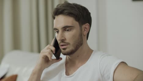 Serious-man-talking-mobile-phone-at-home.-Worried-business-man-call-phone
