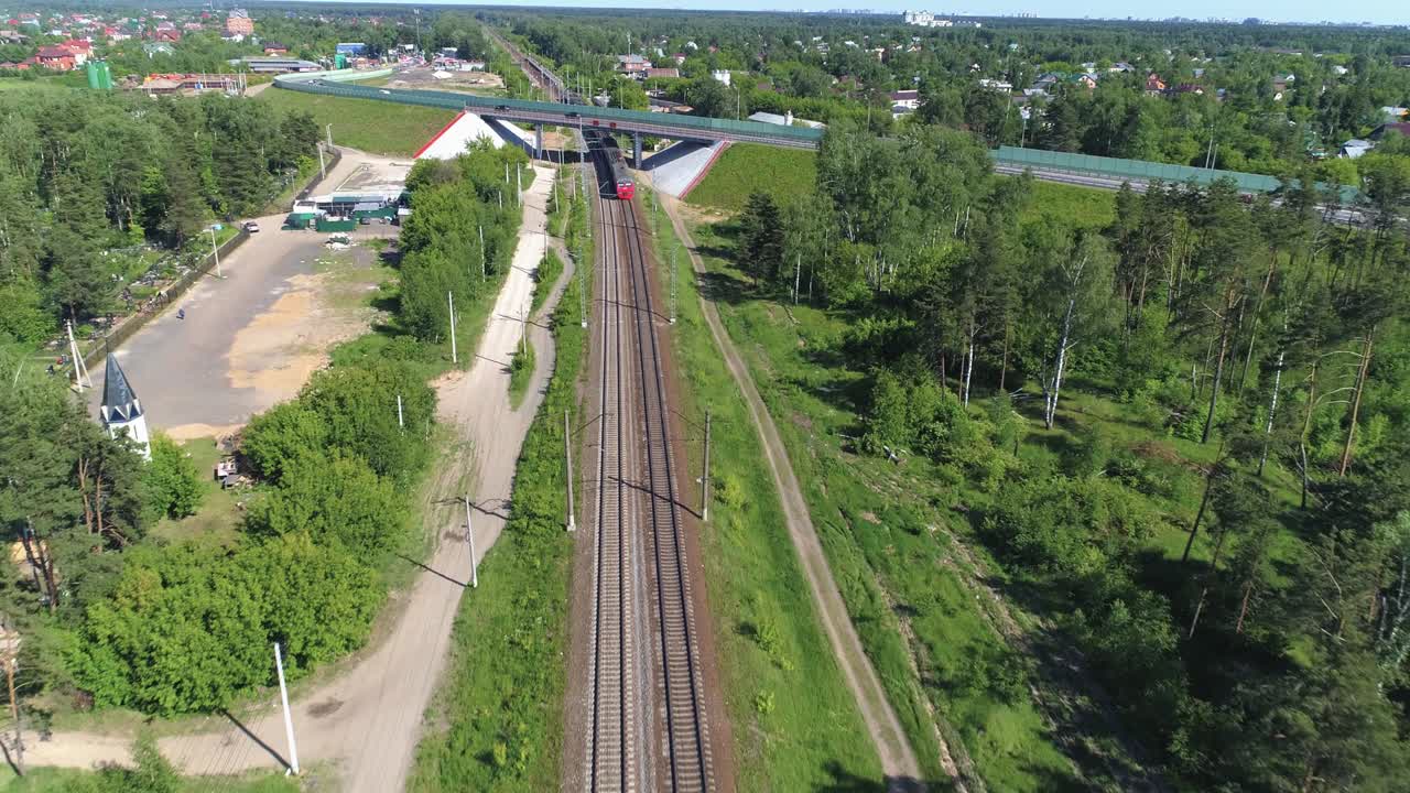 пассажирский электрический поезд уходит на расстояние, проходит под автомобильным мостом