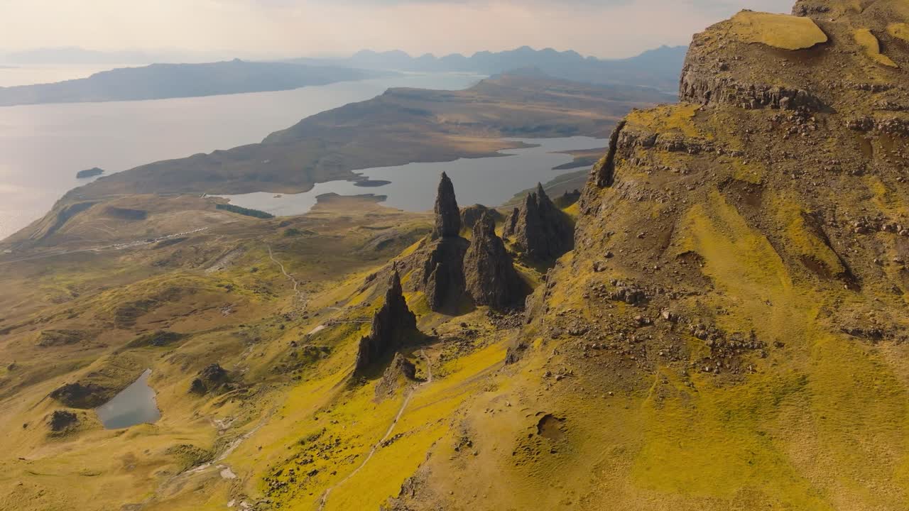 Aerial drone footage of the dramatic mountain landscapes on the Isle of Skye, Scotland. Sweeping panoramic views of majestic peaks, green valleys, and wild nature. Old man of Storr