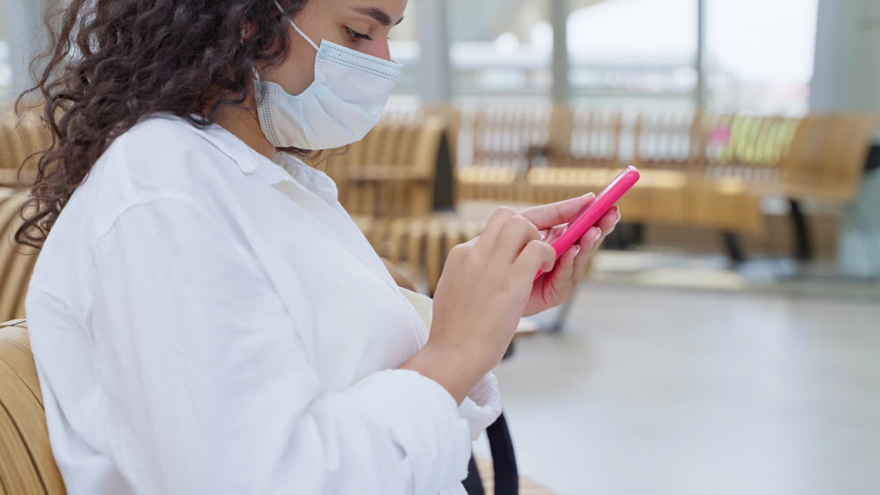 mujer esperando en un centro de transporte con una máscara facial