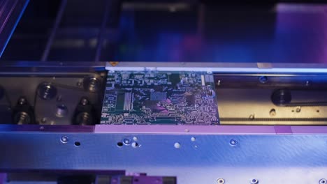 factory machine at work: printed circuit board assembled with automatic robotic arm, surface mount technology connecting microchips to the motherboard