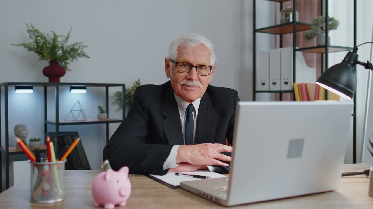 Blid, eldre forretningsmann med briller og formell dress smiler og ser på kameraet