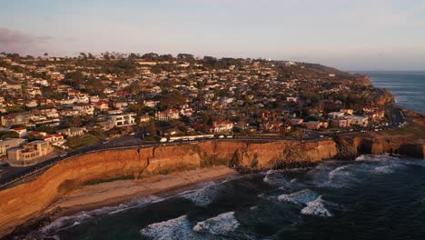 aerial pan at sunset of waves and bluffs and homes on sunset cliffs in san diego