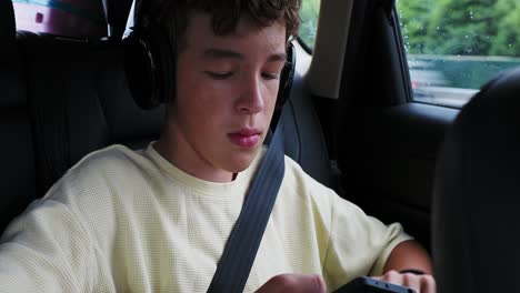 teenager in car with headphones and phone