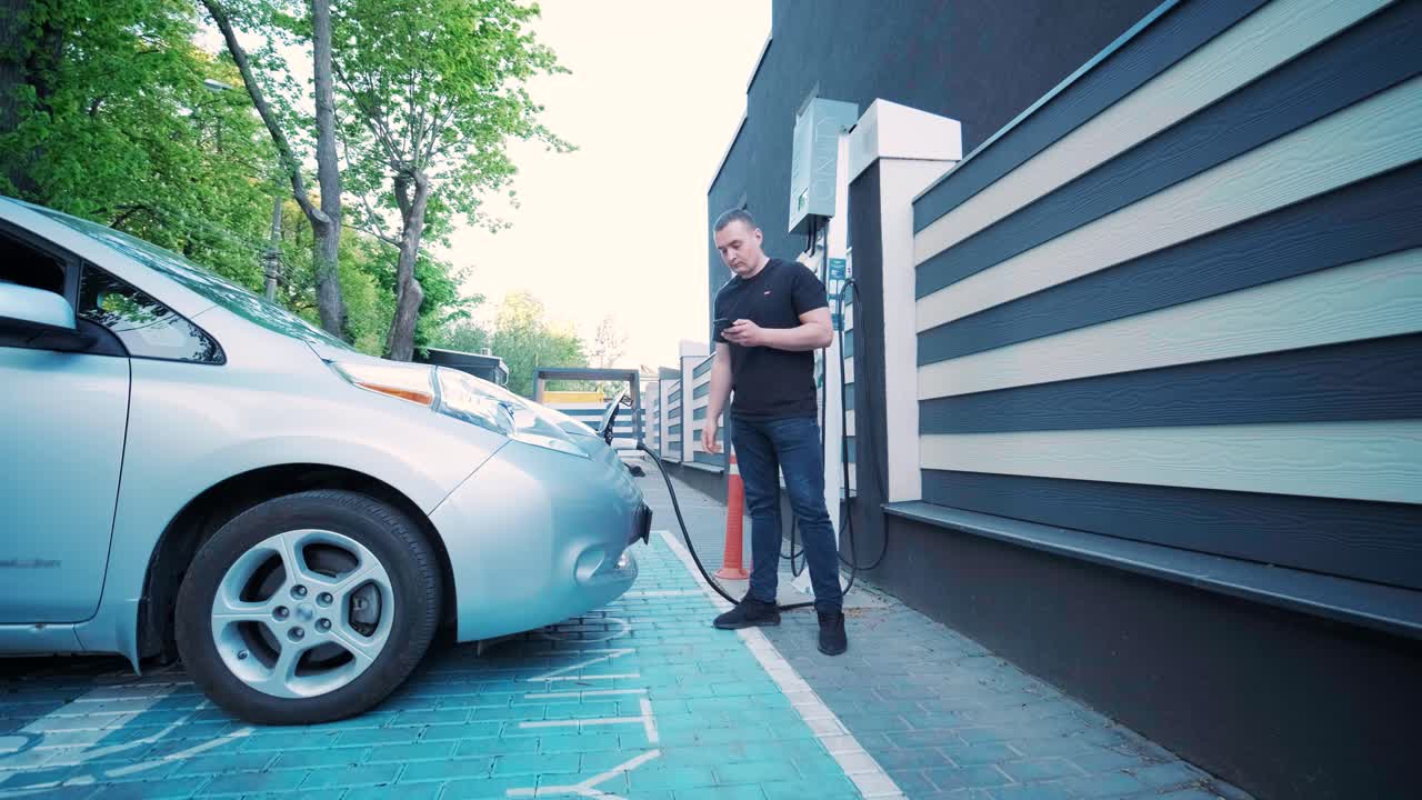 процесс заправки электромобиля. выстрел под люком, где заряжается электрический экомобиль. люк зарядки электрического автомобиля открывается автоматически. мужская рука вставляет эректильную машину
