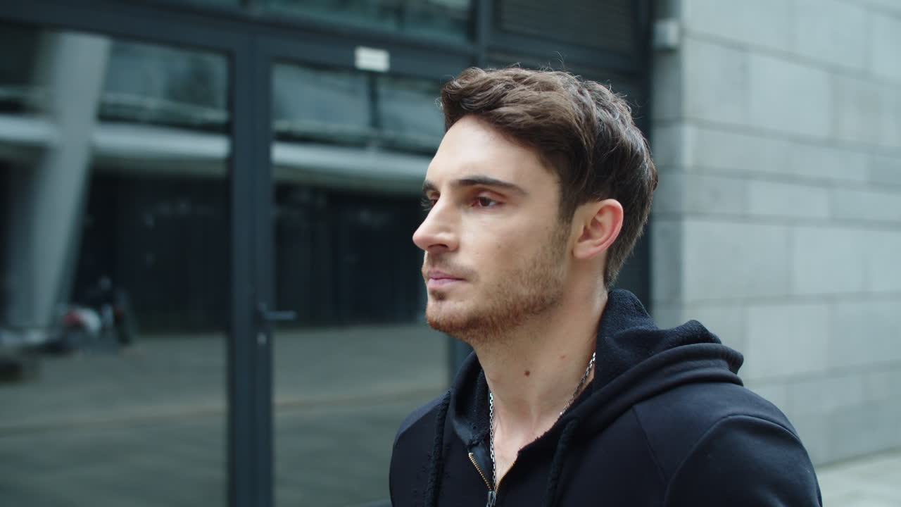 Portrait of young man walking street. Close up attractive guy in hoodie