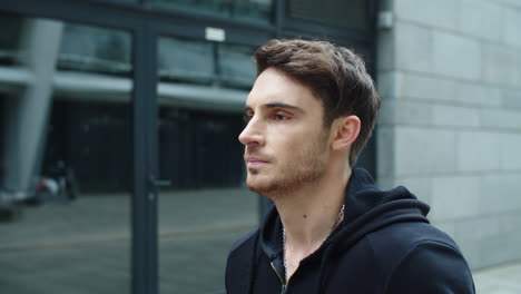 portrait of young man walking street. close up attractive guy in hoodie