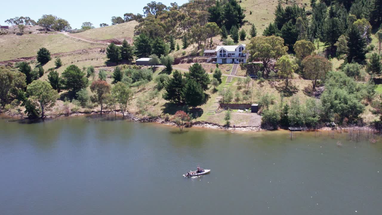 Pulling back ad rising aerial footage of people in a speed boat on lake Eildon, near Mansfield in central Victoria, Australia. The storage was 97% full. February 2024.