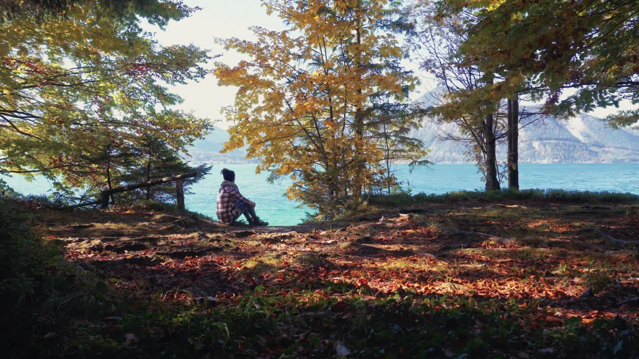 Peaceful autumn scene Cinemagraph. Young woman sitting at Walchensee alpin lake in Bavaria, Germany