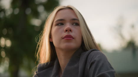 lady in grey shirt deep in thought with sunlight creating a warm, ambient glow around her, soft light reflecting off her face, with a blurred natural background