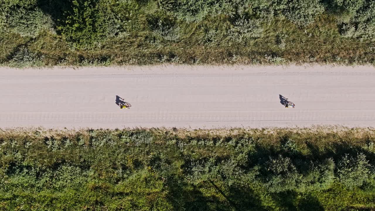 Overhead aerial of two tourists cycling countryside path evokes leisure escape