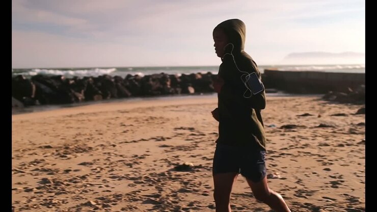 African American male runner jogging on the beach 4k