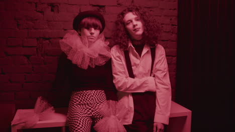 two friends leaning on a table on brick wall.