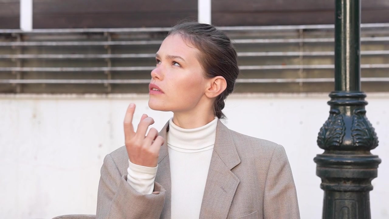 Una giovane donna pensierosa, vestita con un elegante capospalla, posa splendidamente all'aperto nella natura.