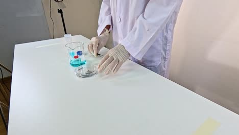 a scientist in a lab coat conducts a copper sulfate solution experiment on a white table under bright lighting