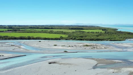 high aerial beside beautiful turquoise rakaia river as it exits into ocean