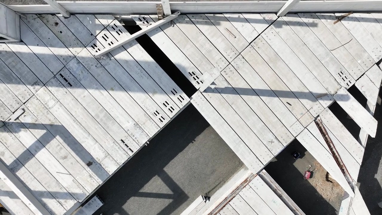 Moderne præfabrikeret betonbygning under opførelse med præfabrikerede søjler, vægpaneler og huldæk, luftfoto