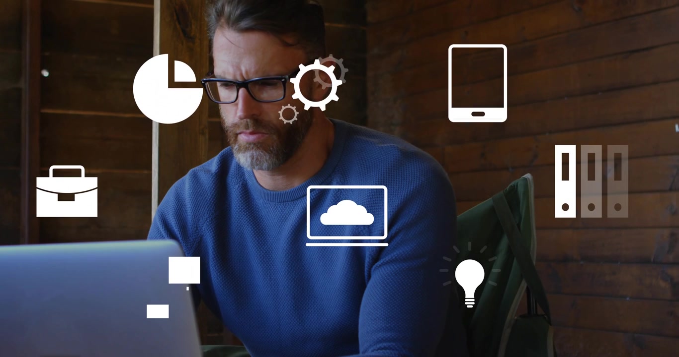 Man typing on laptop at wooden desk, fading business pie chart icons pulsing around him