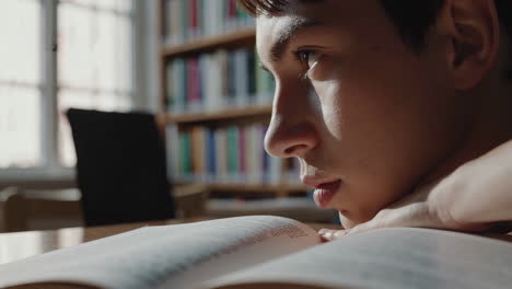 young person reading a book in a library
