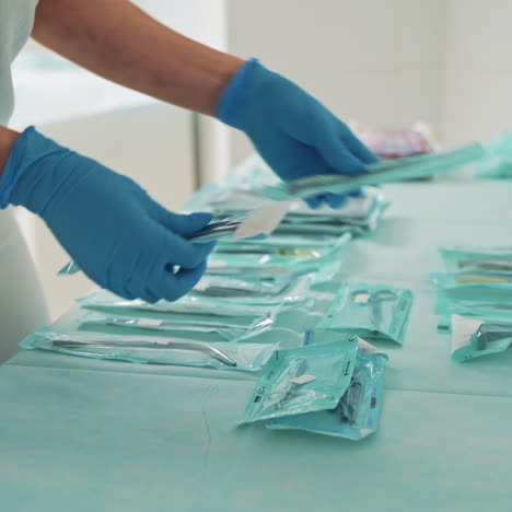 doctor or dentist lays out medical equipment on the table. set of packed sterile instruments for dental treatment. doctor's hands in blue gloves is putting dental tools in stomatology clinic.