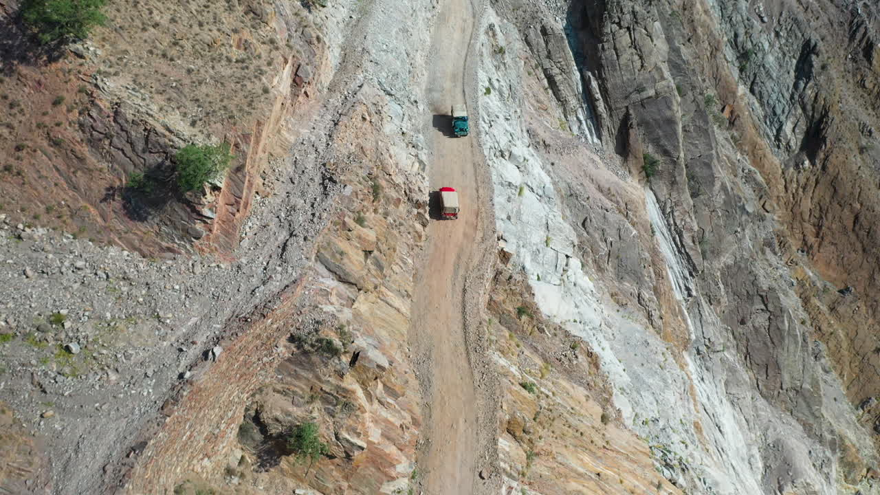 세계에서 두 번째로 치명적인 고속도로인 파키스탄의 요정 초원 도로에서 서로 지나가는 차량의 서사시적인 드론 샷, 넓은 공중 촬영