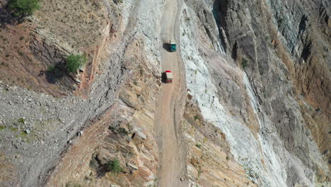 Epic-drone-shot-of-vehicles-passing-each-other-on-Fairy-Meadows-Road-in-Pakistan,-second-deadliest-highway-in-the-world,-wide-aerial-shot