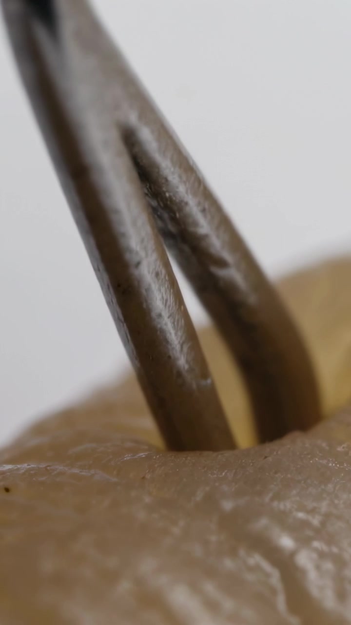 Video verticale: Pinzetta metallica sospesa che si avvicina a un pelo sulla pelle in macro, chiudendosi e tirando per depilare.